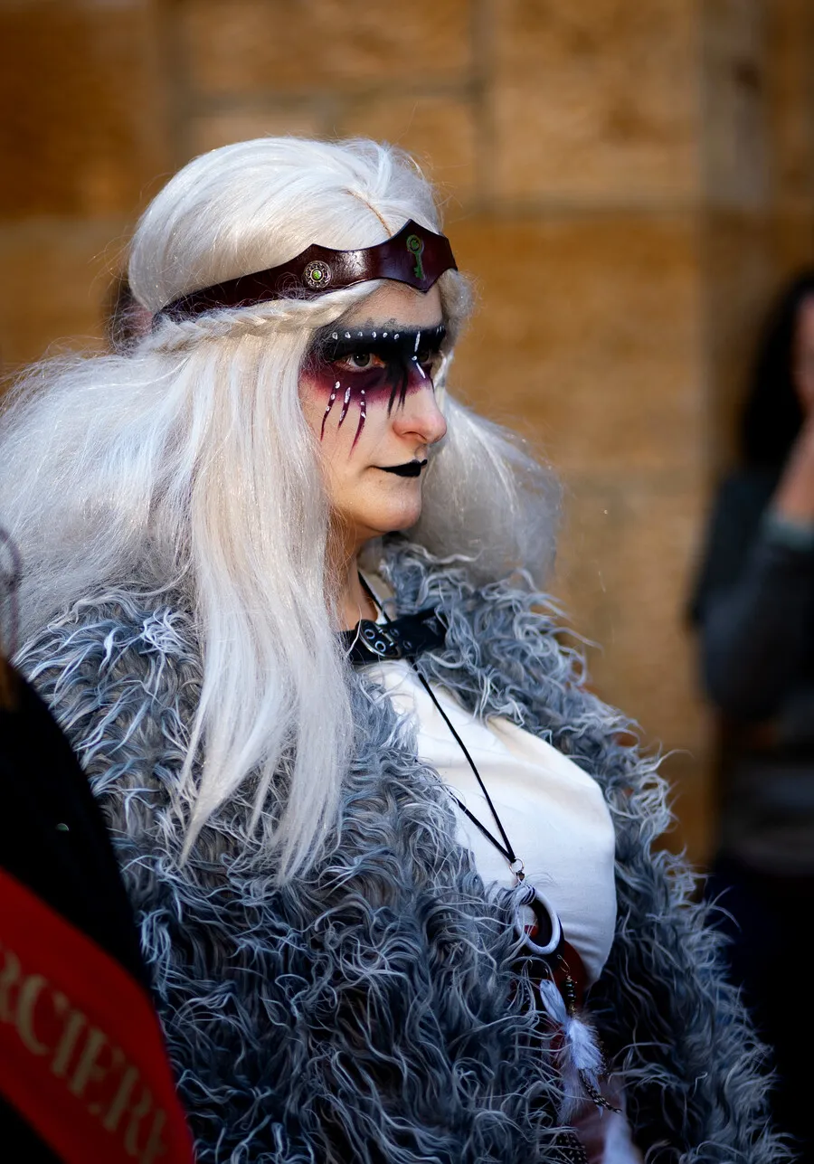 Une sorcière aux cheveux blancs, maquillée de noir, dans la foule du sabbat