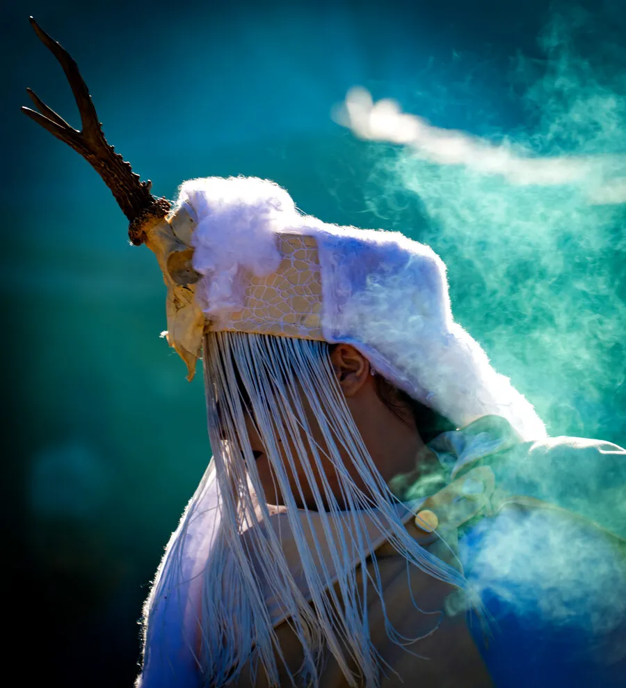 Une coiffe à bois de cerf dans un nuage de fumigène turquoise